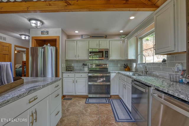 129 Bridgeview Ln, Lafollette, TN 37766 - kitchen featuring appliances with stainless steel finishes, a sink, decorative backsplash, light stone counters, and white cabinetry