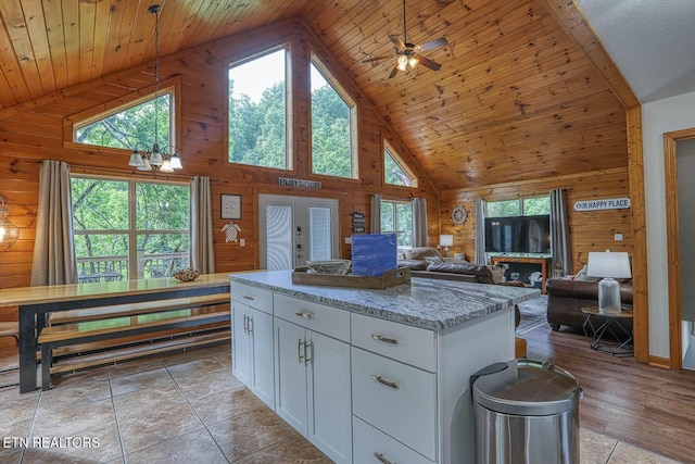 129 Bridgeview Ln, Lafollette, TN 37766 - kitchen with wooden walls, high vaulted ceiling, white cabinets, light stone counters, and a kitchen island