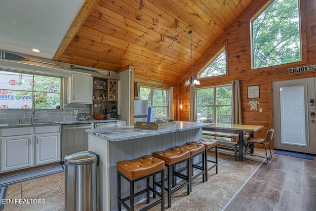 129 Bridgeview Ln, Lafollette, TN 37766 - kitchen featuring stainless steel dishwasher, plenty of natural light, a kitchen island, light stone countertops, and wooden walls