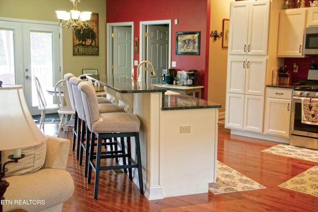 120 Lakeside Dr, Kingston, TN 37763 - kitchen with appliances with stainless steel finishes, wood finished floors, a kitchen bar, dark stone countertops, and a chandelier