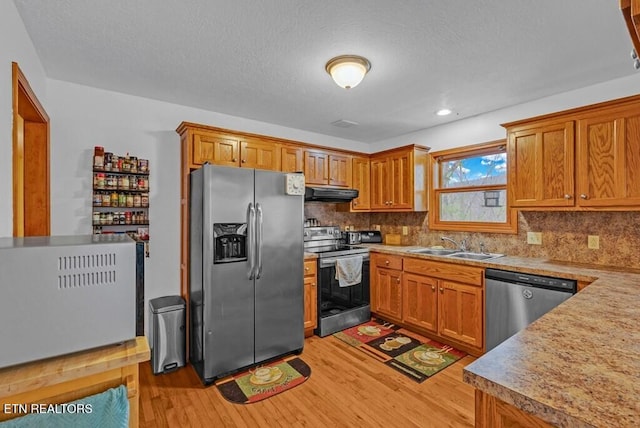 108 W Bobcat Ln, Wilder, TN 38589 - kitchen featuring appliances with stainless steel finishes, under cabinet range hood, light wood-style flooring, a sink, and brown cabinetry