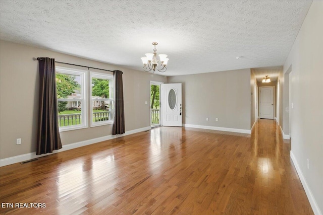 68 Pine Mountain Cir, Pineville, KY 40977 - unfurnished living room with a chandelier, light wood-style flooring, a textured ceiling, and baseboards
