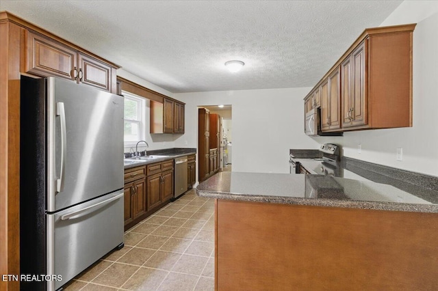 68 Pine Mountain Cir, Pineville, KY 40977 - kitchen featuring appliances with stainless steel finishes, a sink, a peninsula, a textured ceiling, and brown cabinets