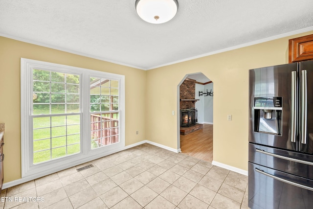 1036 Hawthorn Dr, Cookeville, TN 38501 - unfurnished dining area featuring light tile patterned floors, ornamental molding, arched walkways, a textured ceiling, and a brick fireplace