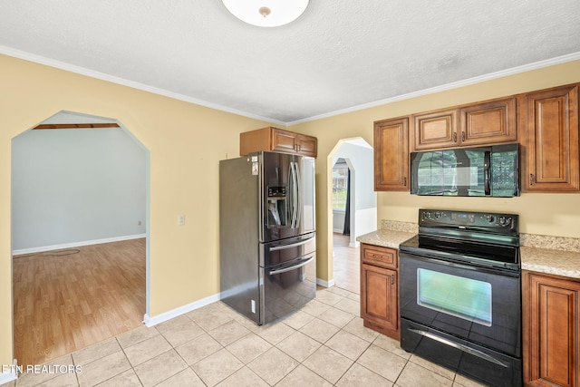 1036 Hawthorn Dr, Cookeville, TN 38501 - kitchen featuring black appliances, arched walkways, brown cabinetry, light tile patterned flooring, and ornamental molding
