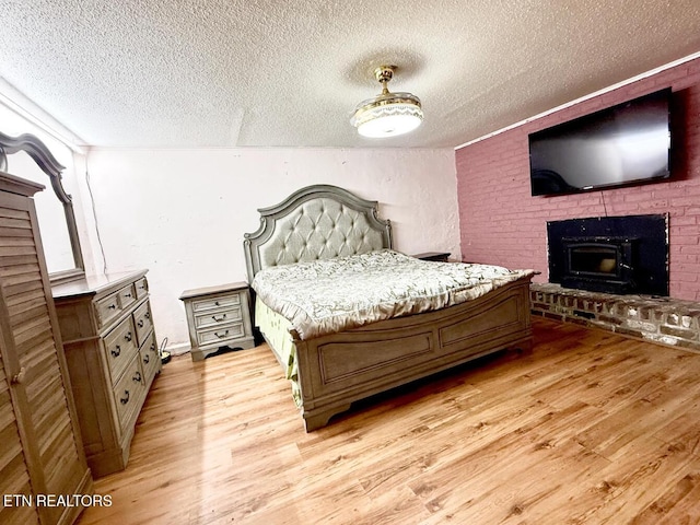 4721 Springcrest Dr, Knoxville, TN 37914 - bedroom with a textured ceiling, light wood-type flooring, and a brick fireplace
