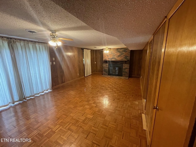 217 Newport Rd Unit 5, Knoxville, TN 37934 - unfurnished living room with a ceiling fan, a brick fireplace, a textured ceiling, wood walls, and baseboards