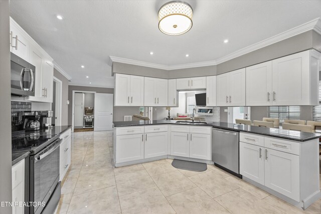 2837 Willa View Dr, Pigeon Forge, TN 37863 - kitchen featuring appliances with stainless steel finishes, a peninsula, crown molding, dark countertops, and white cabinets