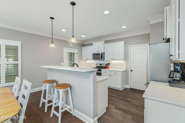 128 Hackberry St, Oak Ridge, TN 37830 - kitchen featuring appliances with stainless steel finishes, ornamental molding, light countertops, white cabinetry, and a breakfast bar area
