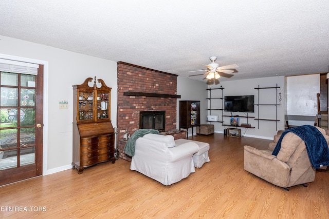 1502 Woodbury Ct, Maryville, TN 37803 - living room with light wood-style floors, a textured ceiling, ceiling fan, a brick fireplace, and baseboards