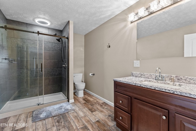 2055 Scott St, Sevierville, TN 37876 - full bathroom featuring toilet, vanity, a textured ceiling, a shower stall, and wood finished floors