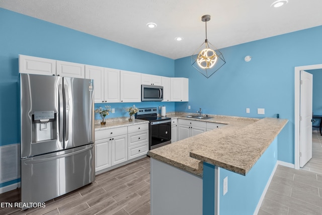 2055 Scott St, Sevierville, TN 37876 - kitchen with appliances with stainless steel finishes, a sink, a peninsula, white cabinets, and decorative light fixtures