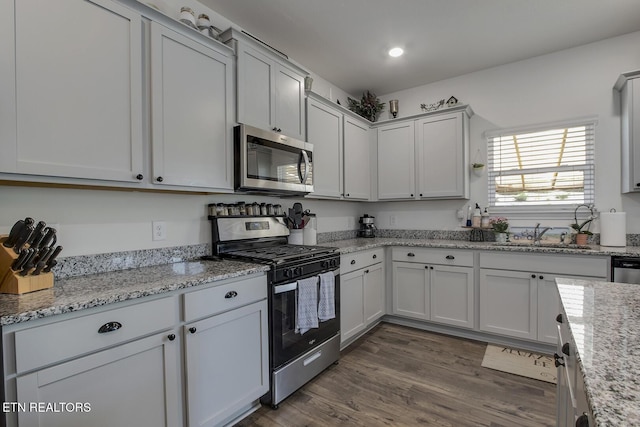12017 Spearmint Ln, Knoxville, TN 37932 - kitchen featuring stainless steel appliances, a sink, dark wood finished floors, light stone counters, and recessed lighting