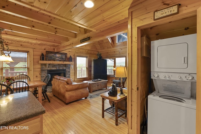 2405 Autumn Valley Way, Pigeon Forge, TN 37862 - living room with stacked washer and clothes dryer, wooden walls, light wood-style flooring, beamed ceiling, and a stone fireplace