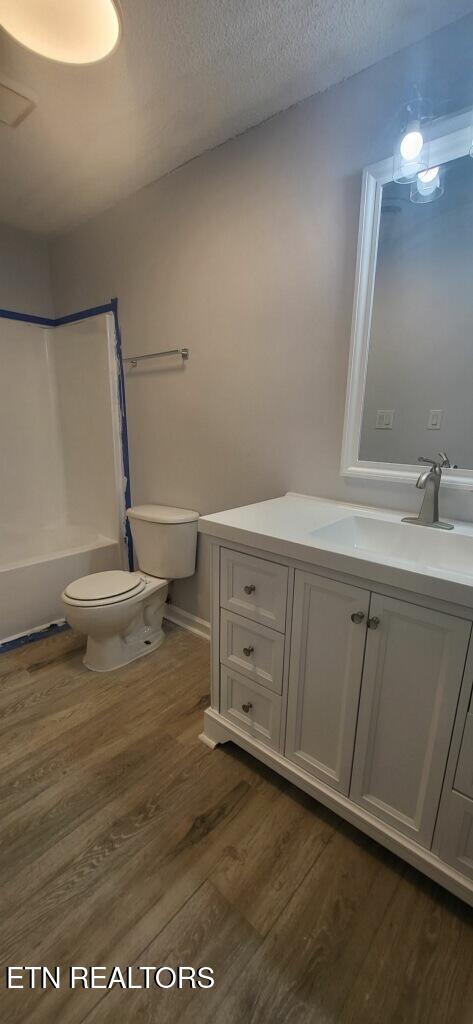 1304 Holyoke St, Kingsport, TN 37664 - full bath featuring toilet, vanity, wood finished floors, shower / washtub combination, and a textured ceiling