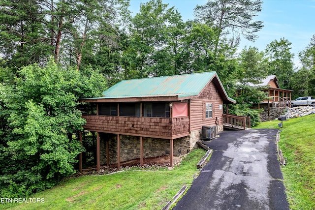 2015 Piney Overlook Ln, Sevierville, TN 37862 - chalet / cabin with stone siding, a sunroom, a front lawn, a metal roof, and asphalt driveway