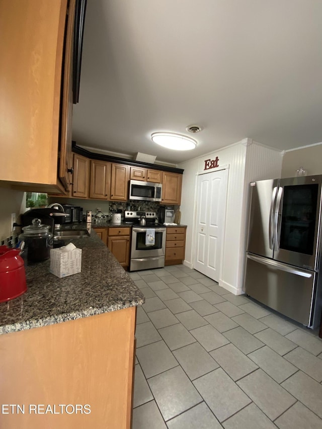 106 Apache Rd, Maryville, TN 37804 - kitchen featuring stainless steel appliances, light tile patterned floors, a sink, brown cabinets, and dark stone countertops