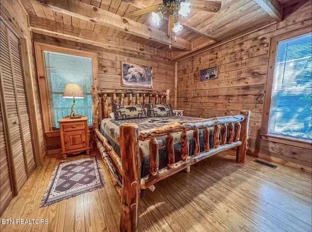 2438 Walnut Ridge Way, Sevierville, TN 37862 - bedroom with wooden ceiling with exposed beams, light wood-style flooring, wood walls, multiple windows, and ceiling fan