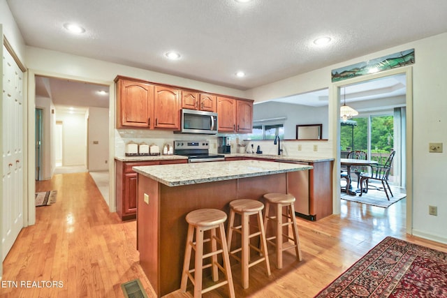 45 Calderwood Cir, Fairfield Glade, TN 38558 - kitchen with appliances with stainless steel finishes, a kitchen island, light wood finished floors, a kitchen bar, and backsplash