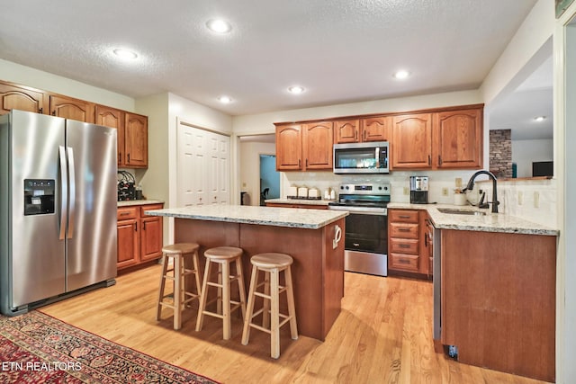 45 Calderwood Cir, Fairfield Glade, TN 38558 - kitchen with stainless steel appliances, a sink, light wood finished floors, a kitchen bar, and a textured ceiling