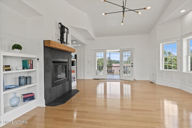 309 Southshore Dr, Greenback, TN 37742 - unfurnished living room with built in features, a decorative wall, light wood finished floors, a tiled fireplace, and a chandelier