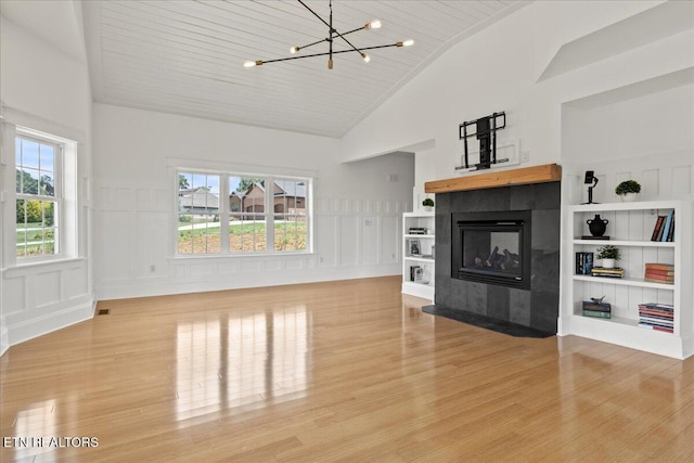 309 Southshore Dr, Greenback, TN 37742 - unfurnished living room with a decorative wall, light wood-style floors, a chandelier, vaulted ceiling, and a fireplace