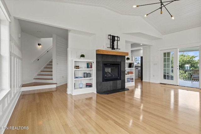 309 Southshore Dr, Greenback, TN 37742 - unfurnished living room featuring light wood-style flooring, vaulted ceiling, a tile fireplace, stairs, and a chandelier