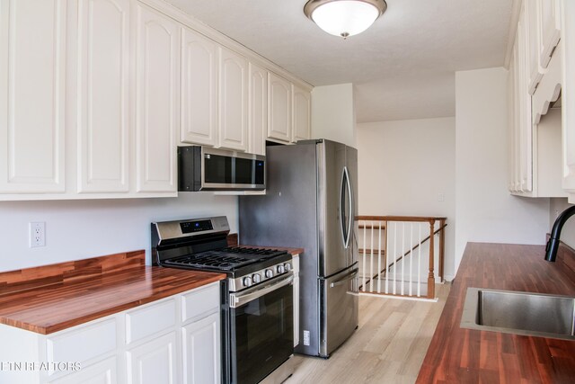 422 Willow Tree Ln, Morristown, TN 37814 - kitchen featuring appliances with stainless steel finishes, butcher block counters, light wood finished floors, and white cabinetry