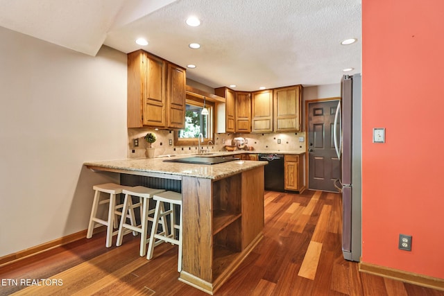104 Maltese Ln, Oak Ridge, TN 37830 - kitchen featuring black appliances, a peninsula, baseboards, dark wood finished floors, and tasteful backsplash