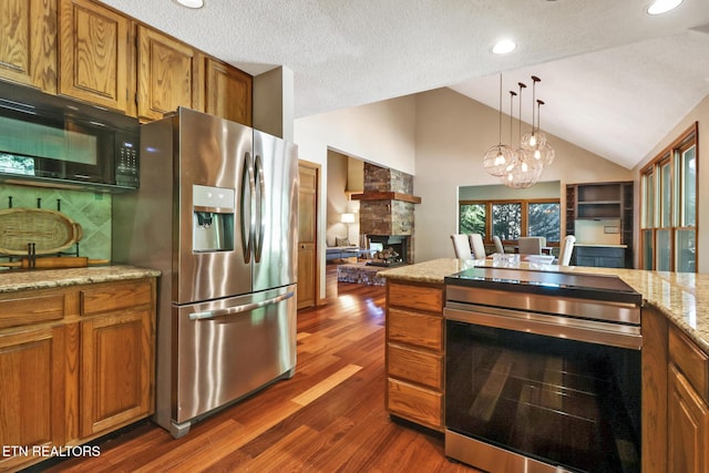 104 Maltese Ln, Oak Ridge, TN 37830 - kitchen with stainless steel appliances, brown cabinetry, dark wood-style flooring, vaulted ceiling, and a fireplace