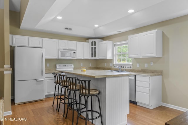 1713 Haley Glenn Ln, Knoxville, TN 37920 - kitchen with white appliances, a center island, a kitchen breakfast bar, white cabinets, and light wood-type flooring
