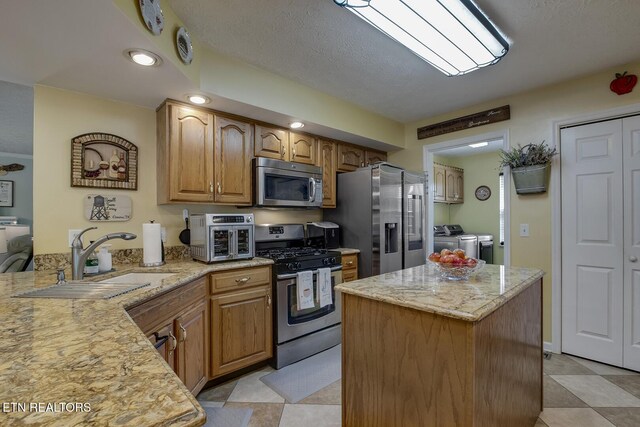 111 Ellis St, Vonore, TN 37885 - kitchen with stainless steel appliances, washing machine and dryer, light stone countertops, a sink, and a kitchen island