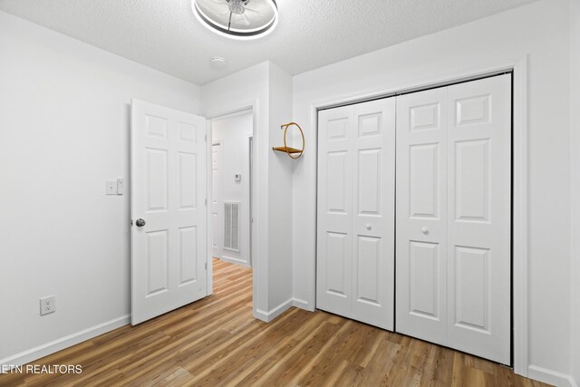 321 Ailey Rd, Dandridge, TN 37725 - unfurnished bedroom featuring light wood-style flooring, a textured ceiling, baseboards, and a closet