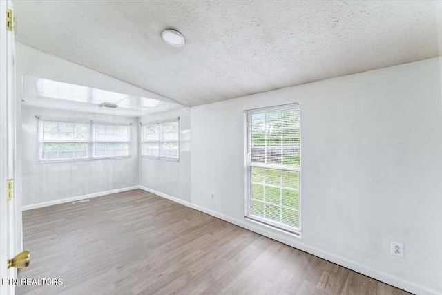 613 Victory St, Knoxville, TN 37919 - empty room featuring wood finished floors, lofted ceiling, baseboards, and a textured ceiling