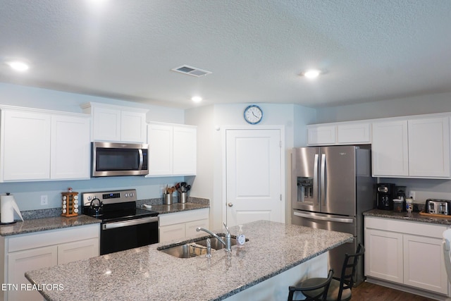5049 Cottonseed Way, Morristown, TN 37813 - kitchen with stainless steel appliances, a sink, a breakfast bar, white cabinetry, and a kitchen island with sink