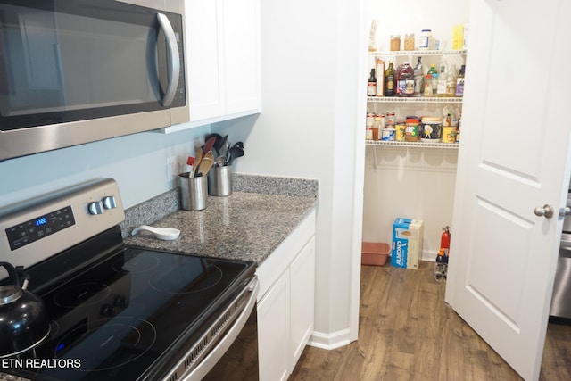 5049 Cottonseed Way, Morristown, TN 37813 - kitchen with stainless steel appliances, white cabinets, dark wood-style floors, stone counters, and baseboards