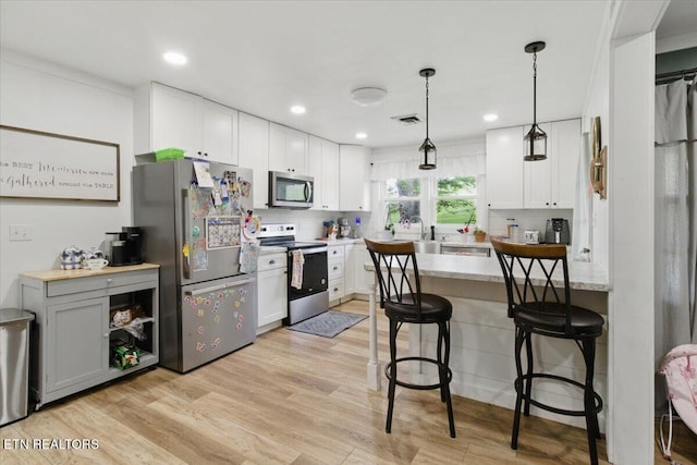 573 Patterson Rd, Harrogate, TN 37752 - kitchen featuring appliances with stainless steel finishes, a peninsula, light wood finished floors, a kitchen bar, and white cabinetry