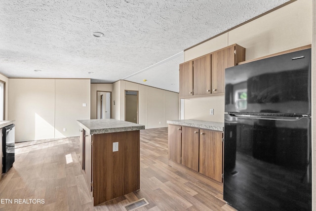 2000 Velma Rd, Athens, TN 37303 - kitchen with freestanding refrigerator, light wood-style floors, a kitchen island, brown cabinets, and a textured ceiling