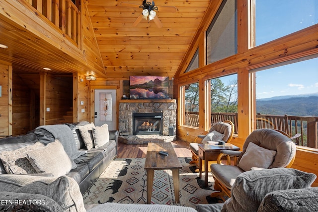 2456 Hackberry Dr, Sevierville, TN 37862 - living room featuring wooden walls, wood finished floors, high vaulted ceiling, ceiling fan, and a fireplace