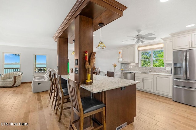 3728 Lighthouse Way, Sevierville, TN 37876 - kitchen featuring appliances with stainless steel finishes, backsplash, ceiling fan, light wood-style floors, and a kitchen bar