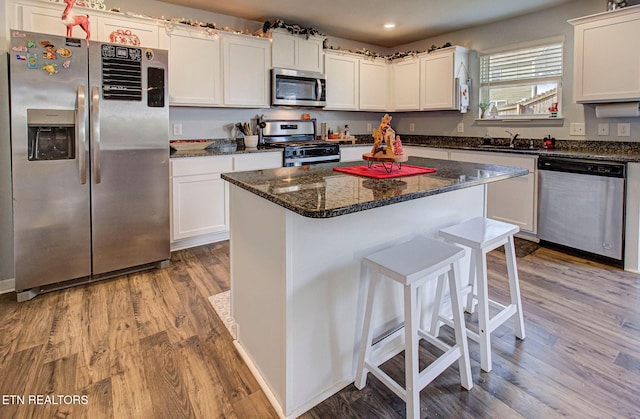 812 Greene Meadow Dr, Talbott, TN 37877 - kitchen with stainless steel appliances, wood finished floors, white cabinetry, a breakfast bar, and a kitchen island