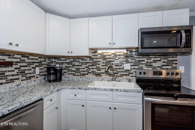 201 Kingston St, Lenoir City, TN 37771 - kitchen featuring appliances with stainless steel finishes, a sink, white cabinets, tasteful backsplash, and a textured ceiling