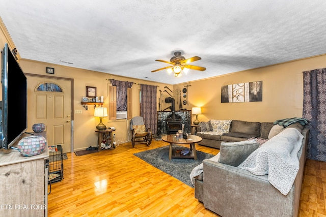 1069 Bryan View Rd, Sevierville, TN 37862 - living room featuring ceiling fan, a wood stove, light wood-style flooring, a textured ceiling, and baseboards