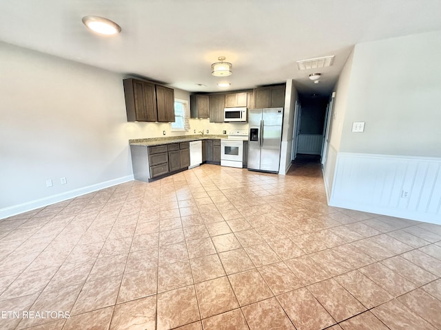 304 Douglas Ave, Knoxville, TN 37921 - kitchen with white appliances, light countertops, dark brown cabinetry, light tile patterned floors, and a wainscoted wall