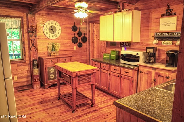 147 Akers Chapel, Jamestown, TN 38556 - kitchen with wood walls, white microwave, light wood-style floors, beamed ceiling, and dark countertops
