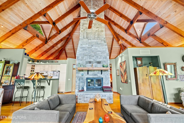 1139 Reagan Valley Rd, Tellico Plains, TN 37385 - living area featuring a wooden ceiling with exposed beams, a ceiling fan, light wood-style flooring, high vaulted ceiling, and a stone fireplace