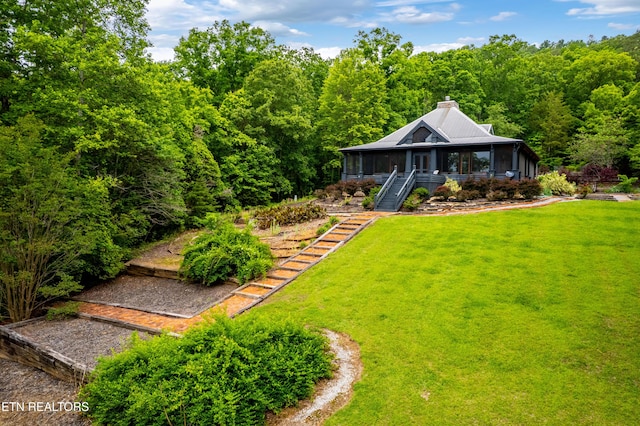 1139 Reagan Valley Rd, Tellico Plains, TN 37385 - view of front of house with stairway, a sunroom, a front lawn, a chimney, and a forest view