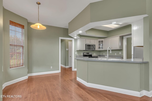 1010 Creek Brook Ln, Seymour, TN 37865 - kitchen featuring stainless steel microwave, electric range, glass insert cabinets, light wood finished floors, and hanging light fixtures