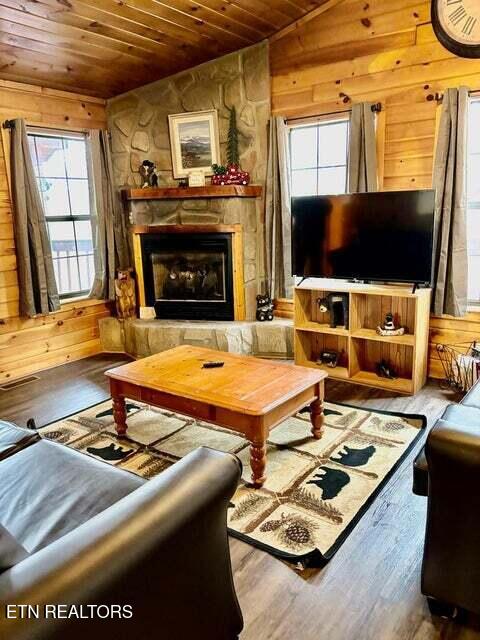 1930 Regans Ridge Way, Sevierville, TN 37876 - living room with wood ceiling, vaulted ceiling, wood finished floors, a stone fireplace, and wooden walls