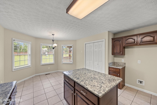 7127 Fieldstone Farms Ln, Knoxville, TN 37921 - kitchen featuring light tile patterned floors, a chandelier, baseboards, a kitchen island, and a textured ceiling